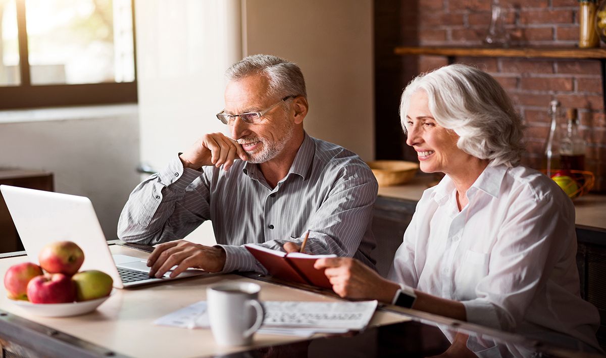 Man in glasses types on computer while wife takes notes